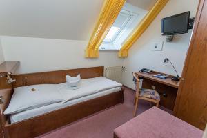 a bedroom with a bed and a desk and a window at Hotel Restaurant Brintrup in Münster