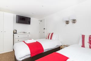 two beds with red and white blankets in a room at Hamptons Brighton in Brighton & Hove