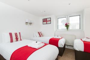 - une chambre avec 3 lits avec des draps rouges et blancs dans l'établissement Hamptons Brighton, à Brighton et Hove