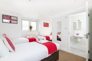 two beds in a white room with a sink at Hamptons Brighton in Brighton & Hove