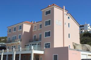 a large pink building with a balcony on the side at O Facho Guest House in Foz do Arelho