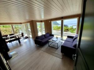 a living room with couches and a table and windows at Explorers Cabin Lofoten in Offersøya