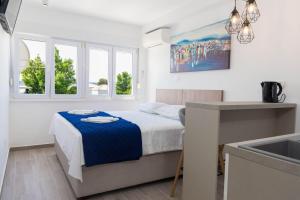 a white bedroom with a bed and a sink at Casteletti in Kaštela
