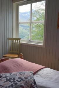 a bedroom with a window and a bed and a chair at Hesthaug Gard in Eidsdal