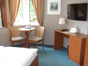 a hotel room with a bed and a desk and a television at Pension & Café Am Krähenberg in Halle an der Saale