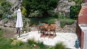 a patio with a table and chairs and an umbrella at Bulgarana in Bourg-Argental