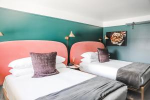 two beds in a room with blue and green walls at RSVP Hotel in Bozeman