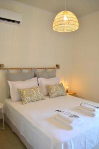ein großes weißes Bett mit Kissen und einem Kronleuchter in der Unterkunft Casa MaLu Boutique Apartments - No 2 in Gouvia
