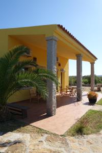 a yellow house with a porch with a bench at Agriturismo Campesi casale tra le vigne in Aglientu