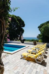 uma fila de espreguiçadeiras amarelas junto a uma piscina em Great view to sea, villa with pool em Salema