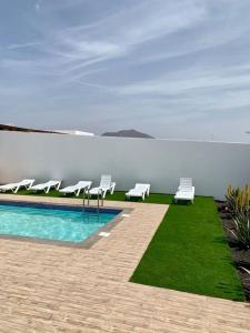 a swimming pool with white chairs next to the water at Casa Nepal in Playa Blanca