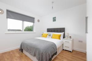 a white bedroom with a bed and a window at Skyvillion - COZY APARTMENTS in Enfield Town With Free Parking & Wifi in Enfield