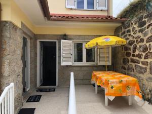 - une table avec un parasol sur la terrasse dans l'établissement Casinha Minhota, à Eirado