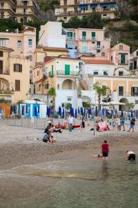 un groupe de personnes sur une plage avec des bâtiments dans l'établissement MARINELLA CASA VACANZE, à Cetara