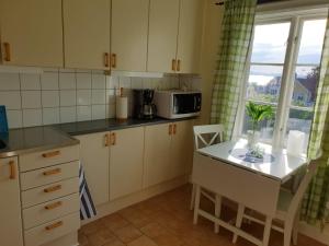 a kitchen with white cabinets and a table and a microwave at Bergsgatan 64 in Gränna