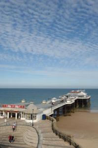 a pier on the beach with people walking on the sand at Hotel De Paris in Cromer