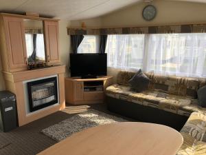 a living room with a couch and a tv and a fireplace at 4 bedroom 10 berth caravans with Hot Tub ,Mountain Bikes Tattershall Lakes in Tattershall