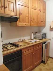 uma cozinha com armários de madeira e um forno com placa de fogão em Bilocale con box - Condominio Cardinello Rosa em Madesimo