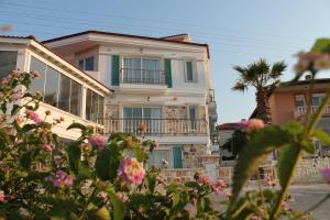a white house with a palm tree and flowers at Alesya Otel in İzmir