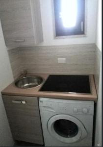 una pequeña cocina con fregadero y lavadora en B&B del Centro, en Veglie