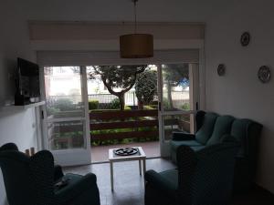 sala de estar con sillas, mesa y ventana en Casa rosiña, en Sanxenxo