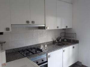 una cocina con armarios blancos y fregadero en Casa rosiña, en Sanxenxo