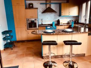 Una cocina con encimera y dos taburetes de bar. en CASA A GUARDA, en A Guarda