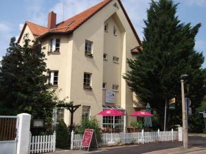 Uma casa com guarda-chuvas cor-de-rosa à frente. em Pension & Café Am Krähenberg em Halle an der Saale