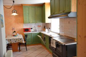 a kitchen with green cabinets and a sink and a table at Appartamento Bruna in Dimaro