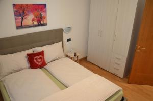 Dormitorio pequeño con cama con almohada roja en Appartamento Bruna, en Dimaro