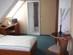 a bedroom with a bed and a desk and a table at Pension & Café Am Krähenberg in Halle an der Saale