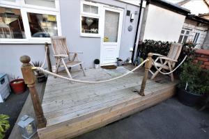 ブラックプールにあるBridle Lodge Apartmentsの椅子2脚とドアが付いた木製のポーチ