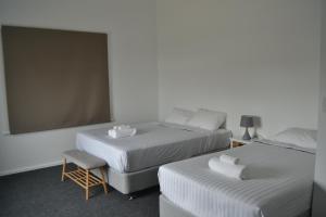 um quarto de hotel com duas camas e uma cadeira em Garden Hotel em Dubbo