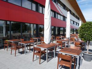 eine Gruppe von Tischen und Stühlen mit Sonnenschirmen außerhalb eines Gebäudes in der Unterkunft Omnium Sport Hotel in Grenchen