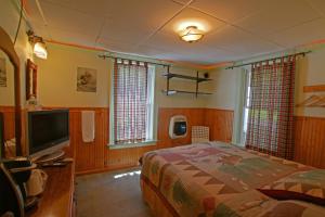 a bedroom with a bed and a flat screen tv at The Big Moose Inn in Big Moose