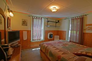 1 dormitorio con 1 cama y TV de pantalla plana en The Big Moose Inn, en Big Moose