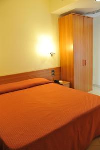 1 dormitorio con 1 cama de color naranja y armario de madera en Hotel Dell'Arpa, en Viggiano