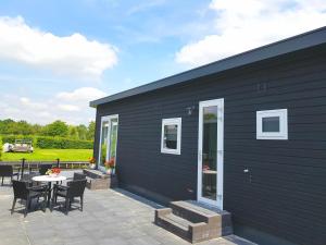 a black house with a patio with a table and chairs at Chalet 15 (Resort Venetië) in Giethoorn