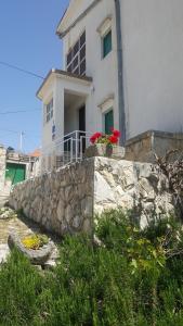 a white house with red flowers on top of a stone wall at David in 5 in Primošten
