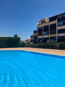 une grande piscine en face d'un bâtiment dans l'établissement Rez de jardin OU ascenseur 4 ieme PISCINE -WIFI-Village naturiste holidaysochic, au Cap d'Agde