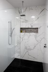a bathroom with a shower with white marble walls at Amooran Oceanside Apartments and Motel in Narooma