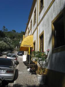 um edifício com um guarda-sol amarelo e mesas e cadeiras em Albergaria do Lageado em Monchique