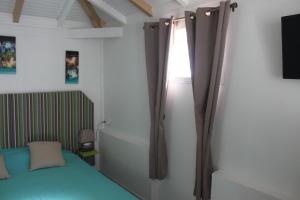 a bedroom with a bed and a window at Résidence B&L Lagon : Bungalow Atoll in Sainte-Luce