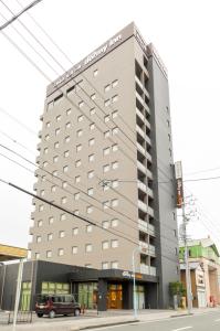挂川市多美迎EXPRESS掛川酒店的一栋高楼，前面停着一辆汽车
