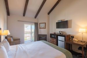 a bedroom with a bed and a desk and a television at Cannery Row Inn in Monterey