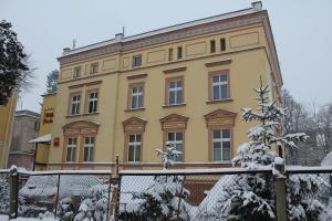 a yellow building with snow in front of it at Willa Podzamcze in Ząbkowice Śląskie