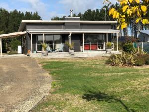 a house with a porch and a yard at Nikau’s on Palmer in Foxton Beach