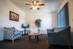 a living room with two chairs and a table and a ceiling fan at Hotel Suites Malena in Ensenada