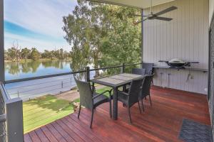 a table and chairs on a deck with a view of the water at Rivergardens Holiday Park Mildura in Gol Gol