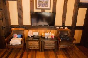 Pokój z 2 krzesłami, biurkiem i telewizorem w obiekcie Black Forest Manor w mieście Ren’ai